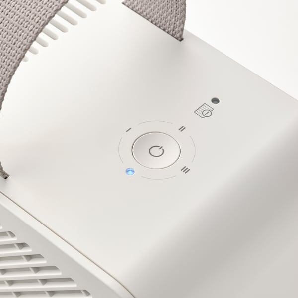 Top view of sleek white air purifier. Central control dial, power button, and indicator light. Modern, minimalist design.
