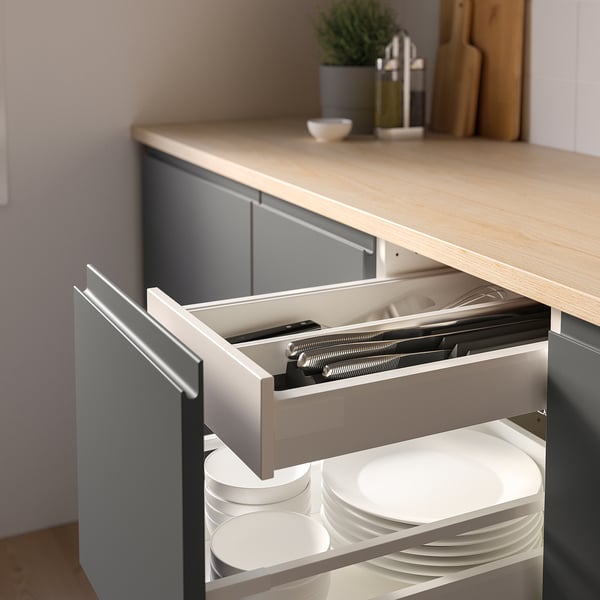 Kitchen drawer with open knife tray, holding knives and white plates.