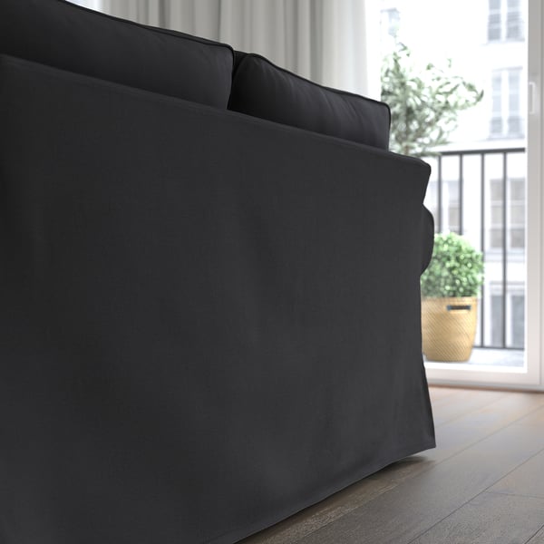 Black UPPLAND sofa with deep, comfy cushions near a window with plants.