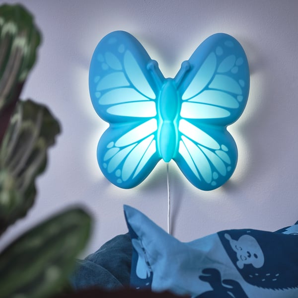 A blue butterfly-shaped nightlight on a wall, emitting soft light, designed for childs room.