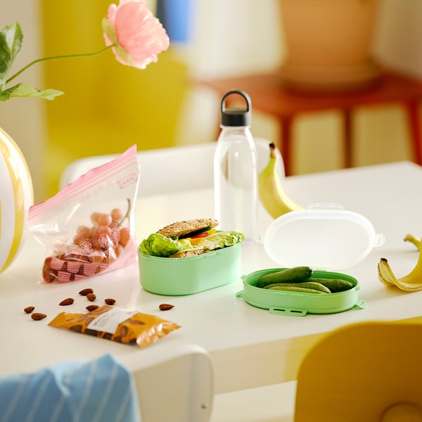 Green UTBJUDA lunchboxes with food & snacks. Flower too.
