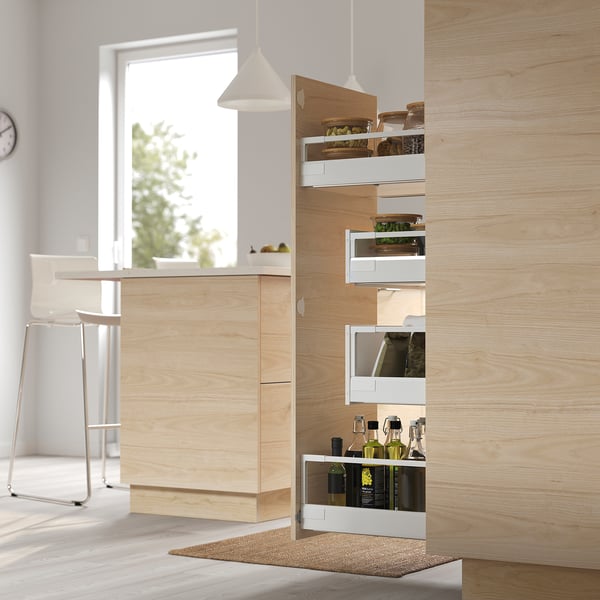 Kitchen cabinet with pull-out pantry, featuring multiple drawers and open shelves displaying bottles and food items.
