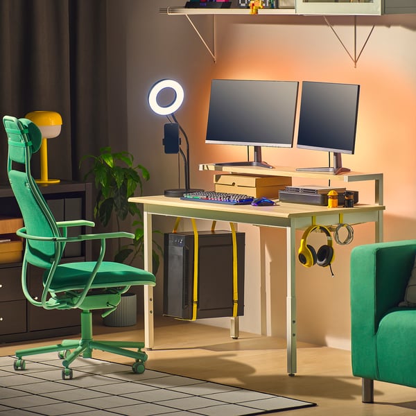 Modern gaming desk with dual monitors, green chair, yellow accents. Compact, organised workspace.