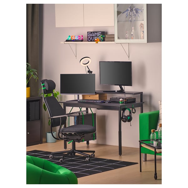 Gaming setup: desk, chairs, dual monitors, accessories, plants.