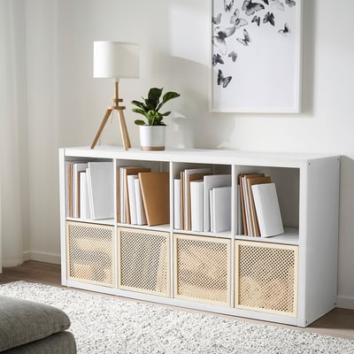 A white våltning cube organiser with books and decor. It includes a lamp, plant, and a butterfly poster.