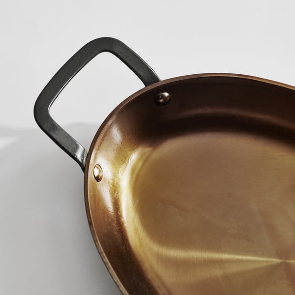 Carbon steel roasting pan with black handles, showing even heat distribution and non-stick surface.