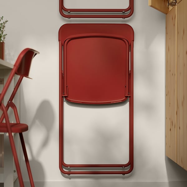 Red folding chairs stacked against a wall. Space-saving design for compact living.