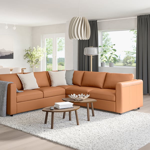 Modern living room with orange VIMLE sofa, coffee tables, rug, large windows, pendant light, and floor lamp.
