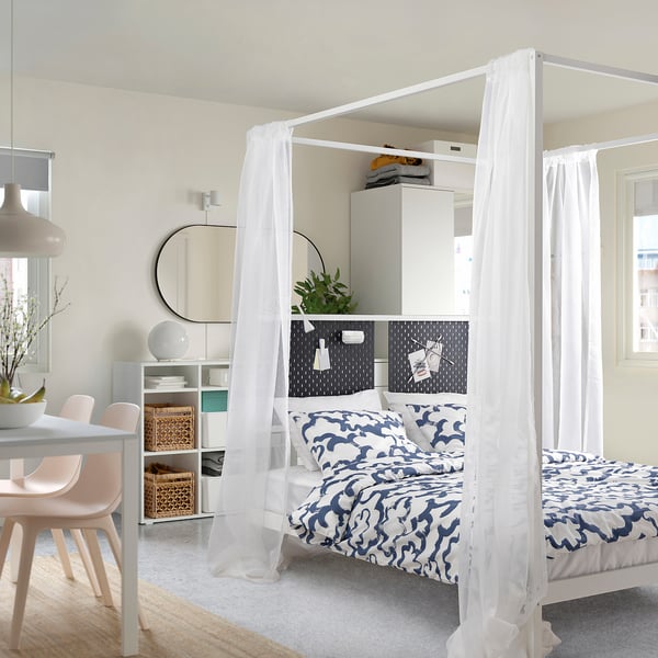 Modern bedroom with VITARNA bed, patterned bedding, small desk, pink chairs.