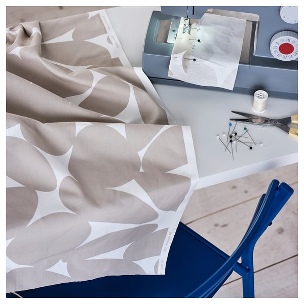 Sewing setup with fabric, scissors, thread, and sewing machine on a table, showcasing a patterned fabric ready for crafting.