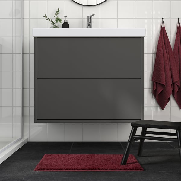 Modern bathroom with BACKMÅRA mat, dark grey, rectangular, under sink, matching red towels and bench.