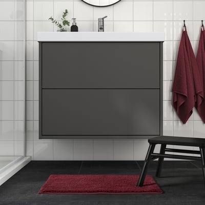 Modern bathroom with BACKMÅRA mat, dark grey, rectangular, under sink, matching red towels and bench.