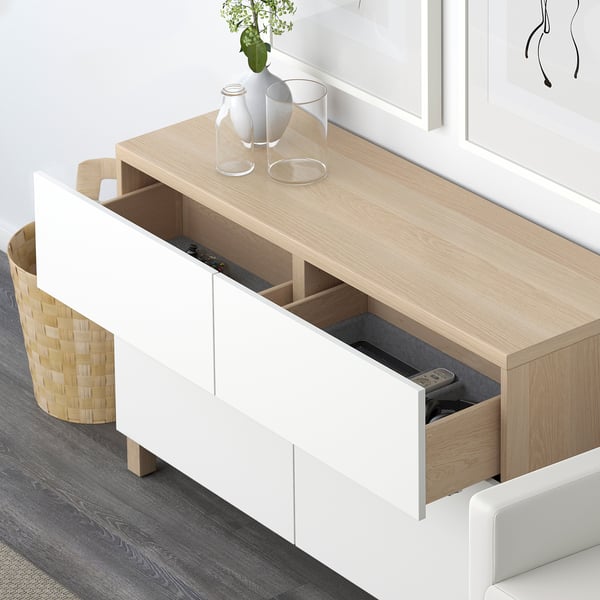 Modern sideboard with open drawers and shelves. Remote and electronic devices stored in visible drawer. Minimalist decor with vases on top.