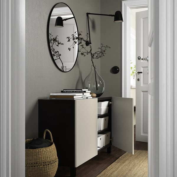Entryway with BESTÅ sideboard, storing items neatly. It adjustable shelves and soft-closing hinges. A basket, vase, and mirror are displayed on top.