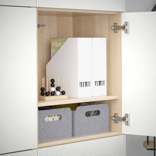 A white BESTÅ storage unit with adjustable shelves, containing grey organiser boxes and decorative items.