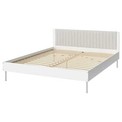 A white BRUKSVARA bed frame with a padded headboard, wooden slats, and metal legs.