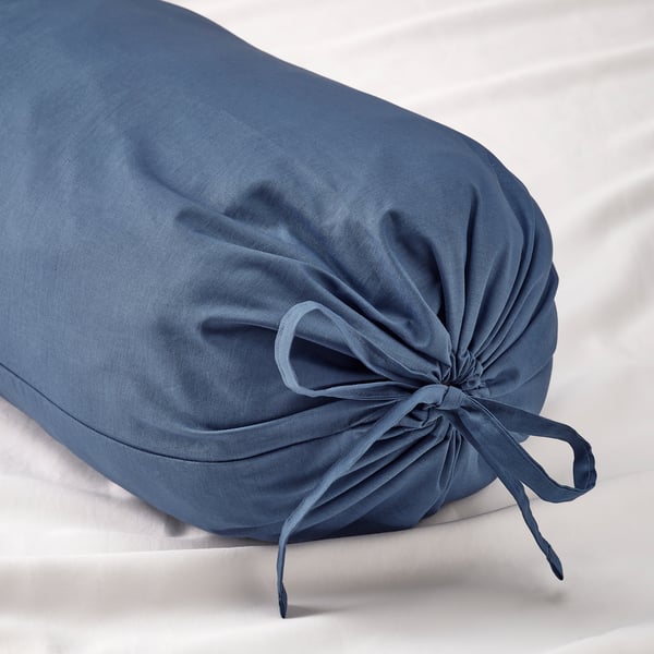 Blue circular bolster pillow with tied fabric ends on white surface.