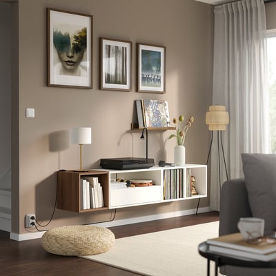 Modern living room with EKET shelves, books, records, and a lamp. Grey armchair, beige rug, and natural-contemporary style.