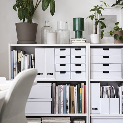Organised home office featuring white FJÄDERHARV magazine files, blending neatly with books and potted plants on shelves.