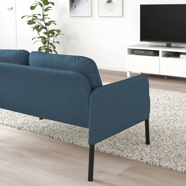 Modern living room with blue GLOSTAD sofa, plant, tv, & rug. Sofas compact, comfy design contrasts with expansive decor.