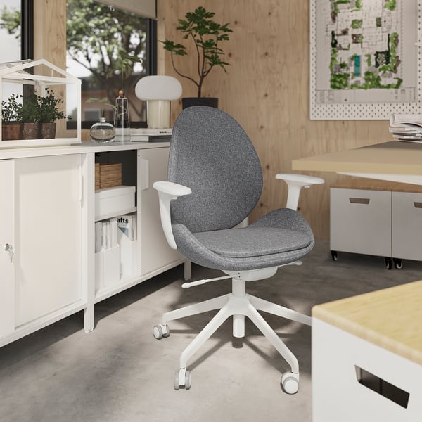 Modern home office with grey ergonomic chair, wooden desk, and plants.