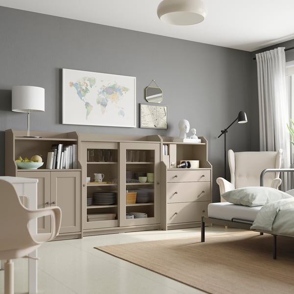 Modern living room with light wood furniture, a world map, mirror, and white armchair.