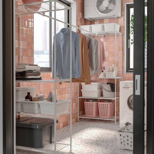 Laundry room with peach tiles, JOSTEIN shelf, blue/brown hangers, towels, baskets.