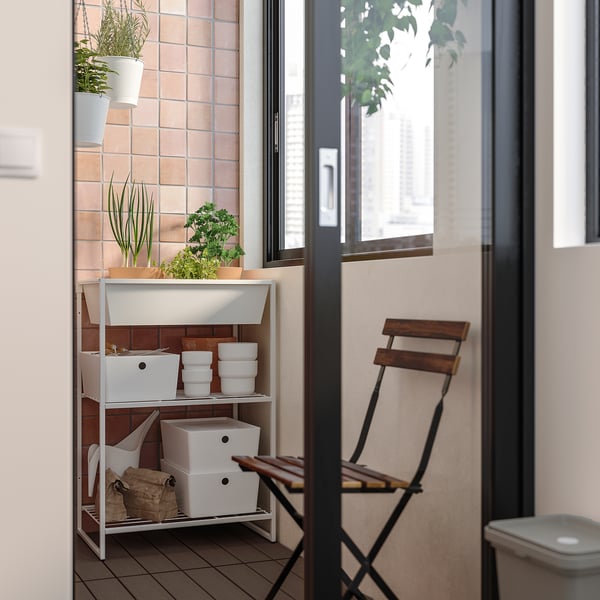 Small outdoor storage unit, white steel, with multiple drawers and pots on top. Ideal for balconies, organised.