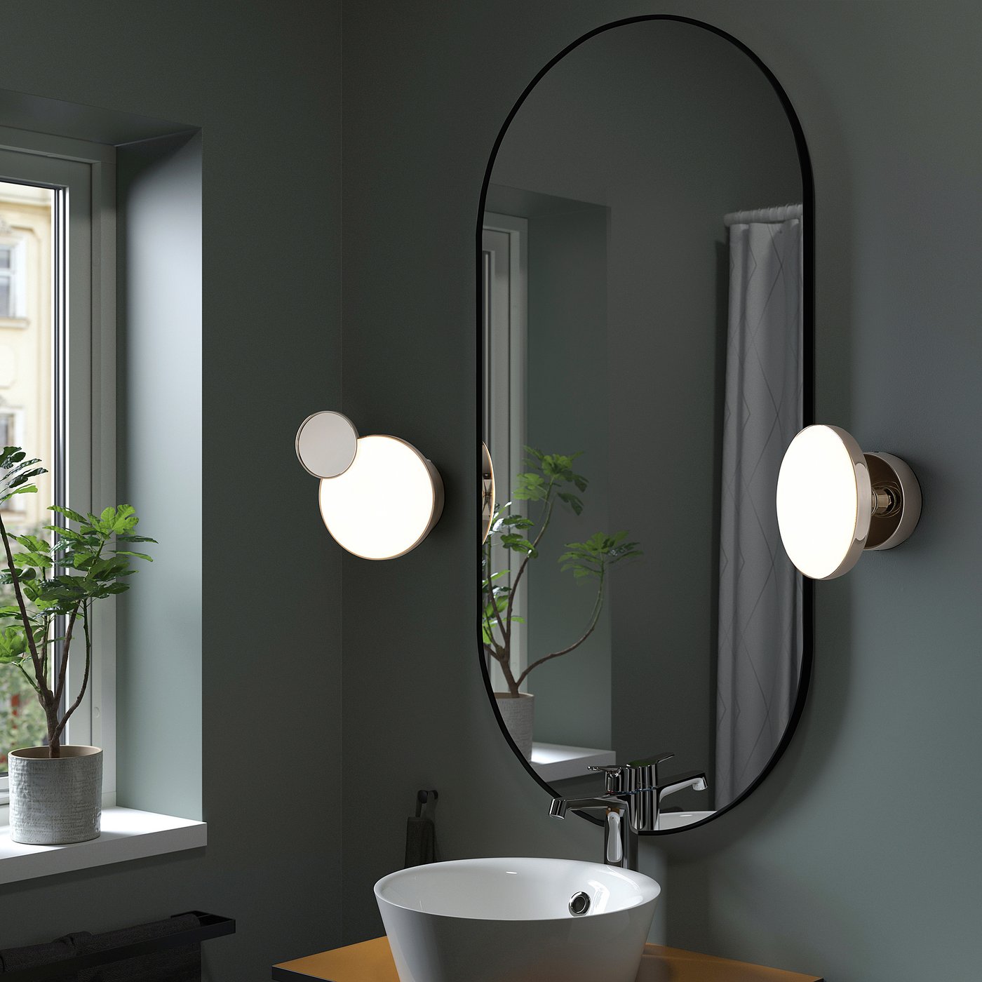 A modern bathroom with a KABOMBA wall lamp featuring a removable mirror, sleek black frame, circular lights, and a small plant on the window sill.