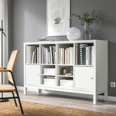 White KALLAX shelf with books, vase, and decor. Modern, closed storage. Smaller than grey wall version.