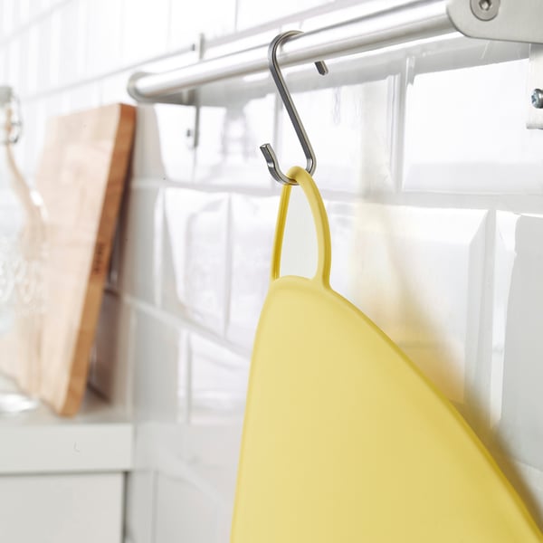 Bright yellow KANONKUL silicone placemat hangs on a metal hook, designed to prevent spills and keep kids food in place.
