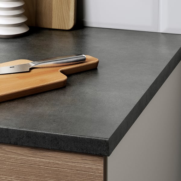 Dark countertop with wooden cutting board and knife, part of a modern kitchen setup.