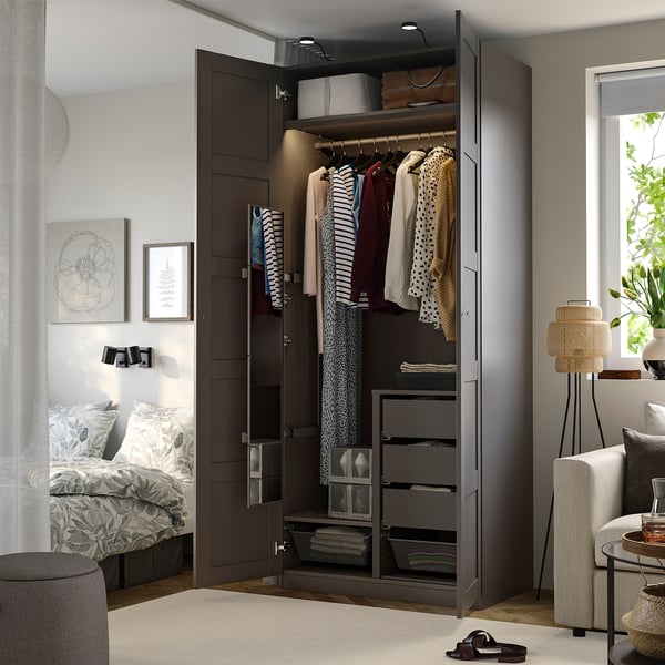Open wardrobe with clothes, mirror, shelves, and drawers inside.