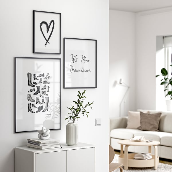 Modern living room with white walls, a light couch, and gallery wall featuring art, a vase, and books.