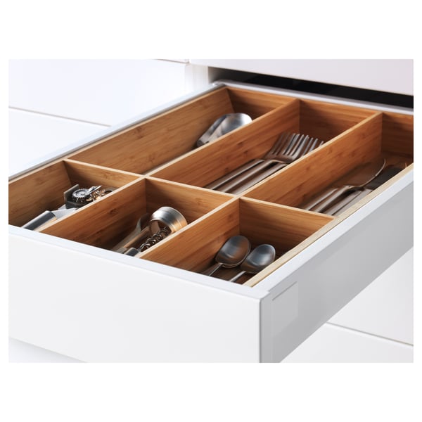 Open white kitchen drawer with bamboo organisers, holding utensils.