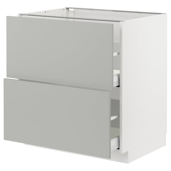Depicts a white METOD cabinet with light grey drawers featuring a modern, clean design.