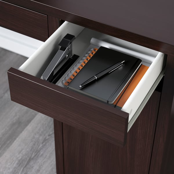 Open desk drawer with notebook, pen, and binder clips, showing adjustable storage.