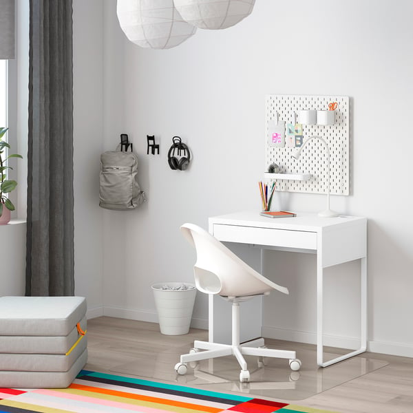 Compact MICKE desk, chair, and pegboard in minimalist room with plant and rug.