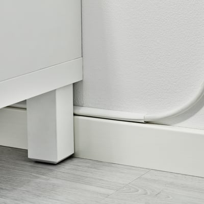 White cable trunking fixed along skirting board, managing and concealing wires neatly.