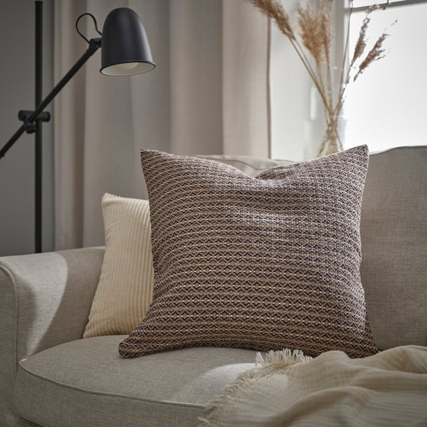 Modern living room with MOROTSMOTT throw pillow, cream pillow, black lamp, and beige blanket on tan sofa.