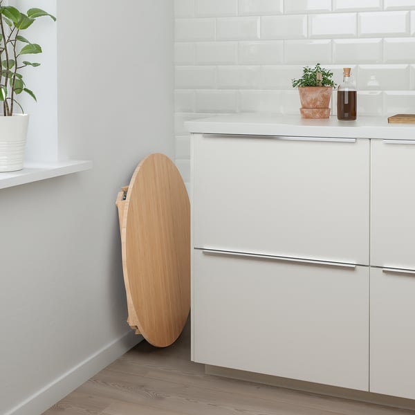Modern kitchen with white cabinets and a bamboo MOXBODA folding table against them.