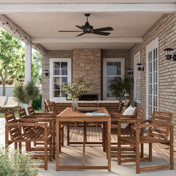 Large wooden patio set with table and chairs. Bright brown colour. Handles several people. Under brick house porch.