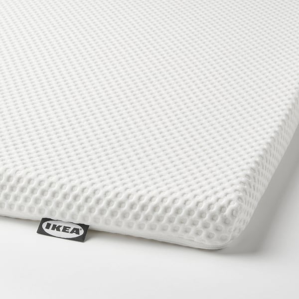 White foam mattress topper with ikea tag, smooth surface for comfort.