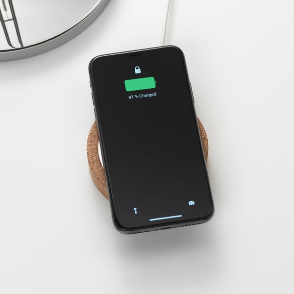 Black smartphone showing 97% charged on wireless cork charger.