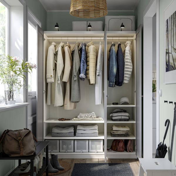 Open closet with coats, jeans, folded clothes, and storage bins, featuring integrated lighting and adjustable shelves.