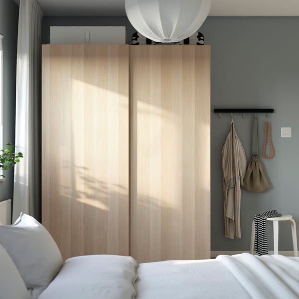 Bedroom with PAX wardrobe, bed, pendant light, and plants.