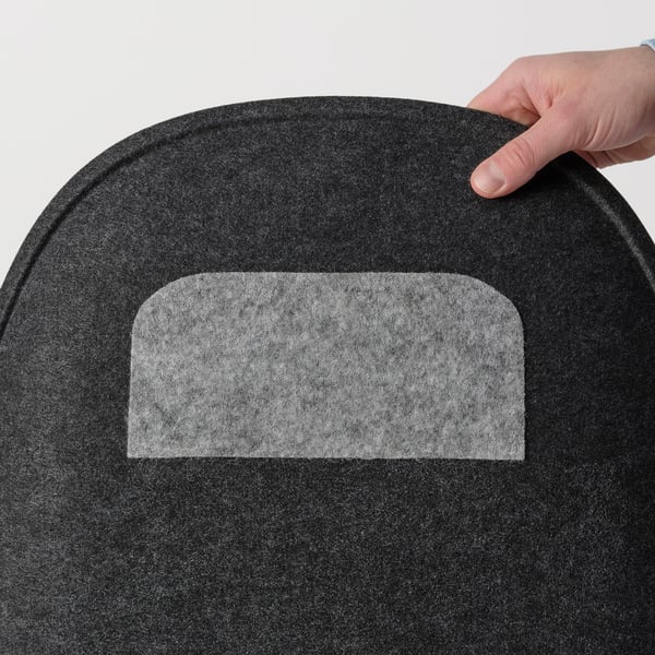 Hand placing soft, black PYNTEN seat pad with non-slip back on white surface.