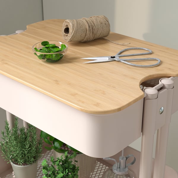 Small wooden-topped pink trolley with scissors, twine, and herbs, ideal for compact spaces.