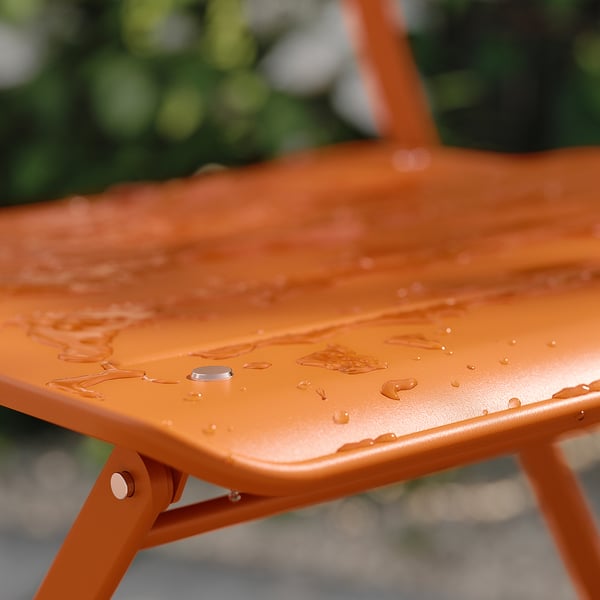 Orange metal patio table with water drops. Folds for easy storage.