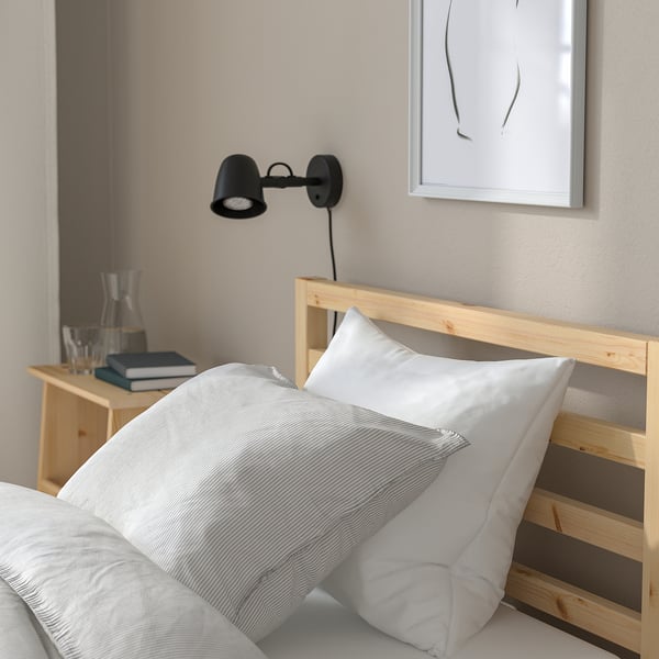 TARVA bed, white linens, black lamp, water carafe, books, abstract art, scandinavian calm.